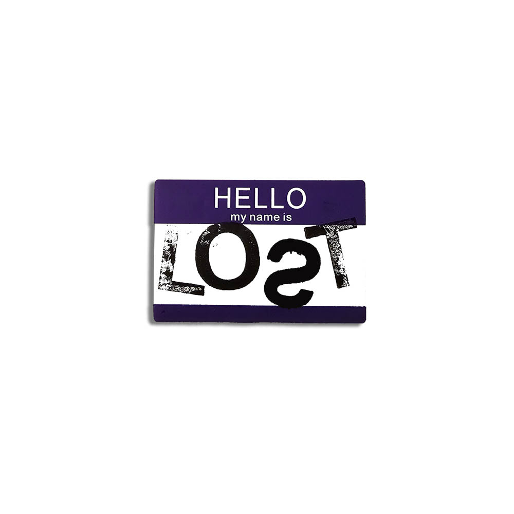 Hello my name is LOST sticker. A purple and white nametag sticker stamped with the name LOST with a backwards S. The sticker is set against a plain white Background.
