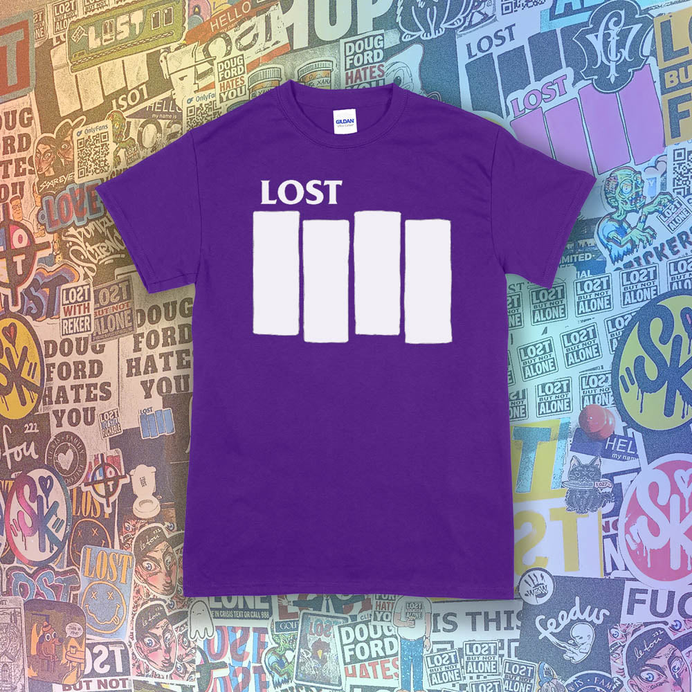The Lost Flag t-shirt. The iconic bold logo is screen printed in white ink on a purple cotton shirt. A collection of colorful graffiti stickers from artists around the world decorate the background.