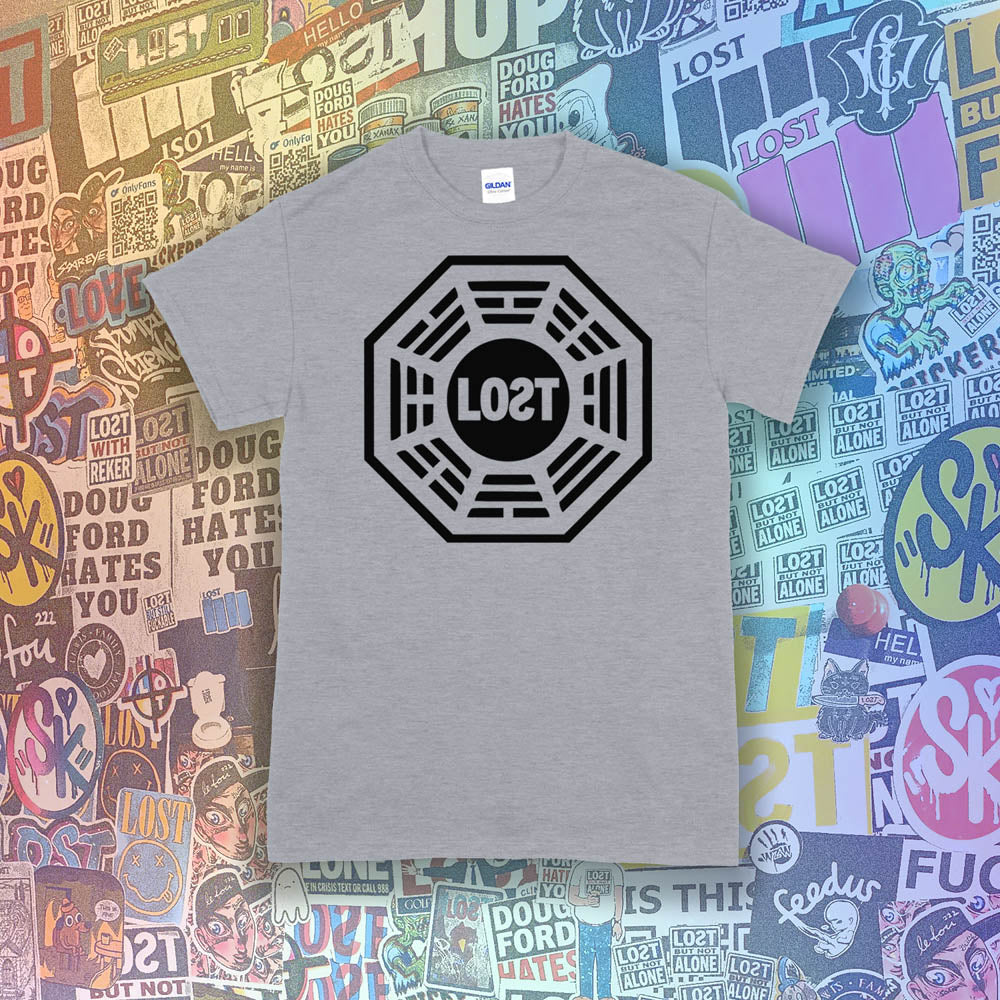 The Lost Initiative t-shirt by Lost Streetwear. The bold black logo is screen printed on a light grey shirt. A wall of brightly colored graffiti stickers from artists around the world provides a background for the shirt.
