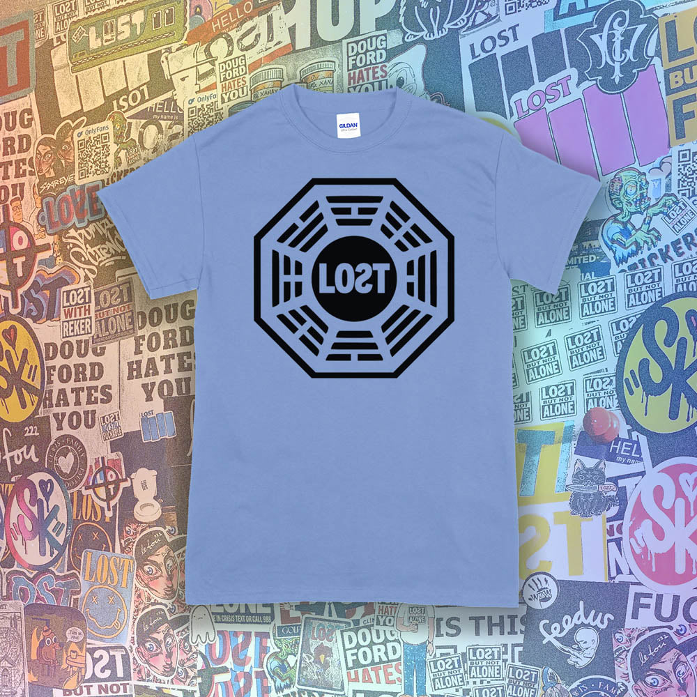 The Lost Initiative t-shirt by Lost Streetwear. The bold black logo is screen printed on a Carolina blue shirt. A wall of brightly colored graffiti stickers from artists around the world provides a background for the shirt.