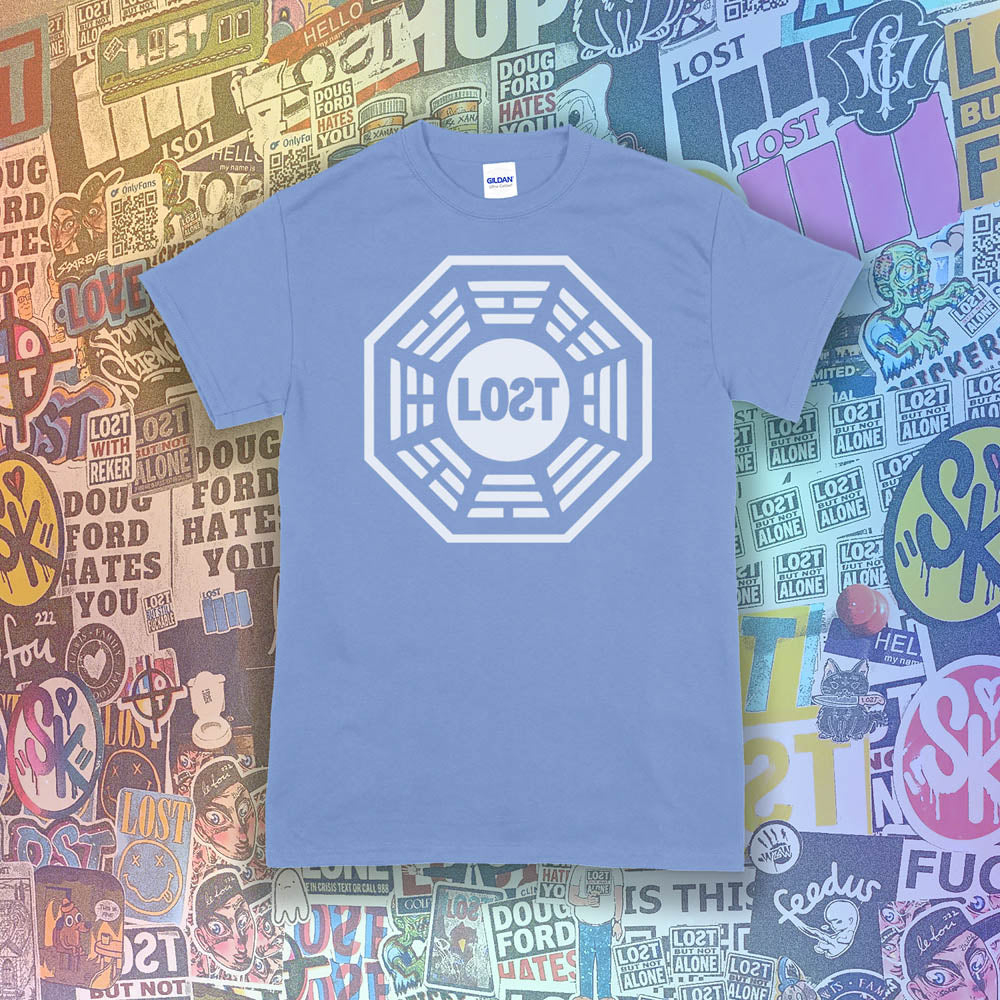 The Lost Initiative t-shirt with a large solid white logo screen printed on a light blue shirt. A collection of colorful graffiti stickers from artists all over the world make up the background.
