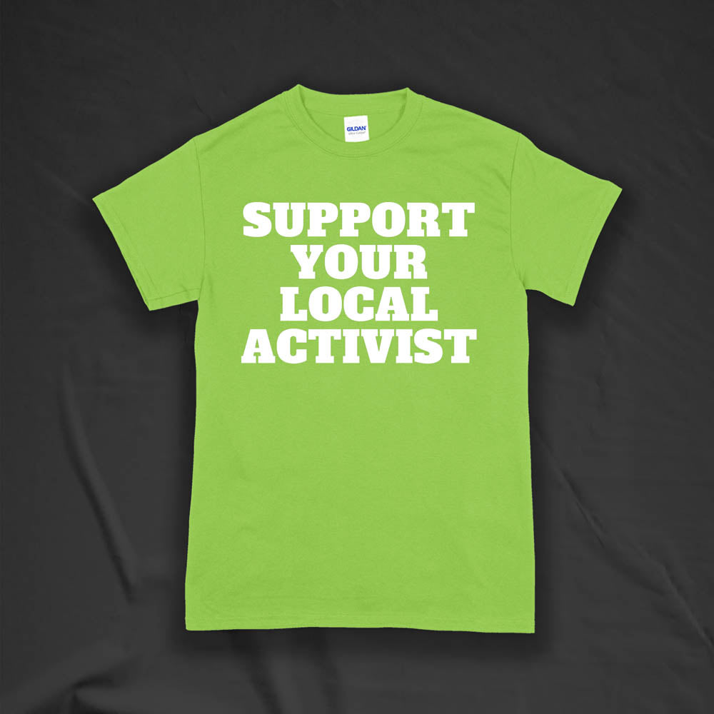 The original Support Your Local Activist t-shirt by LOST. Bold white letters screen printed on a lime green shirt. The shirt is displayed against a textured black background.