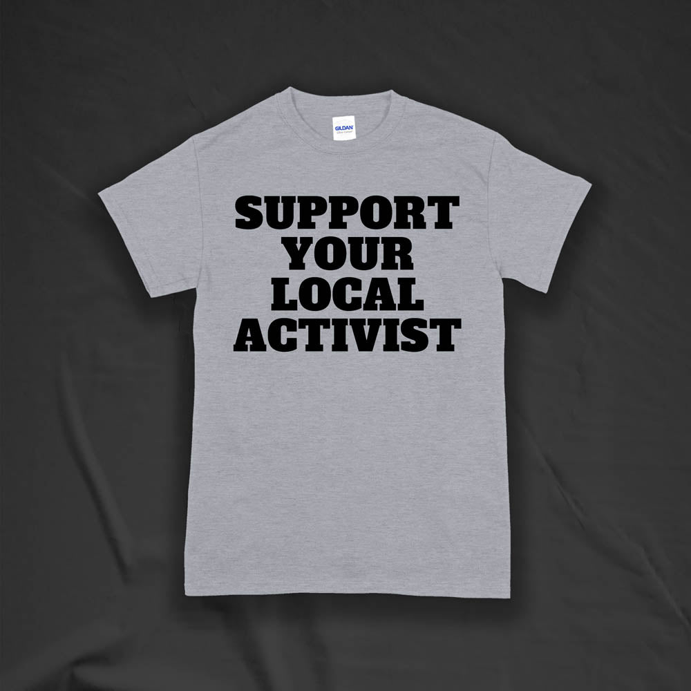 The original Support Your Local Activist t-shirt by LOST. Bold black letters screen printed on a gray shirt. The shirt is displayed against a textured black background.