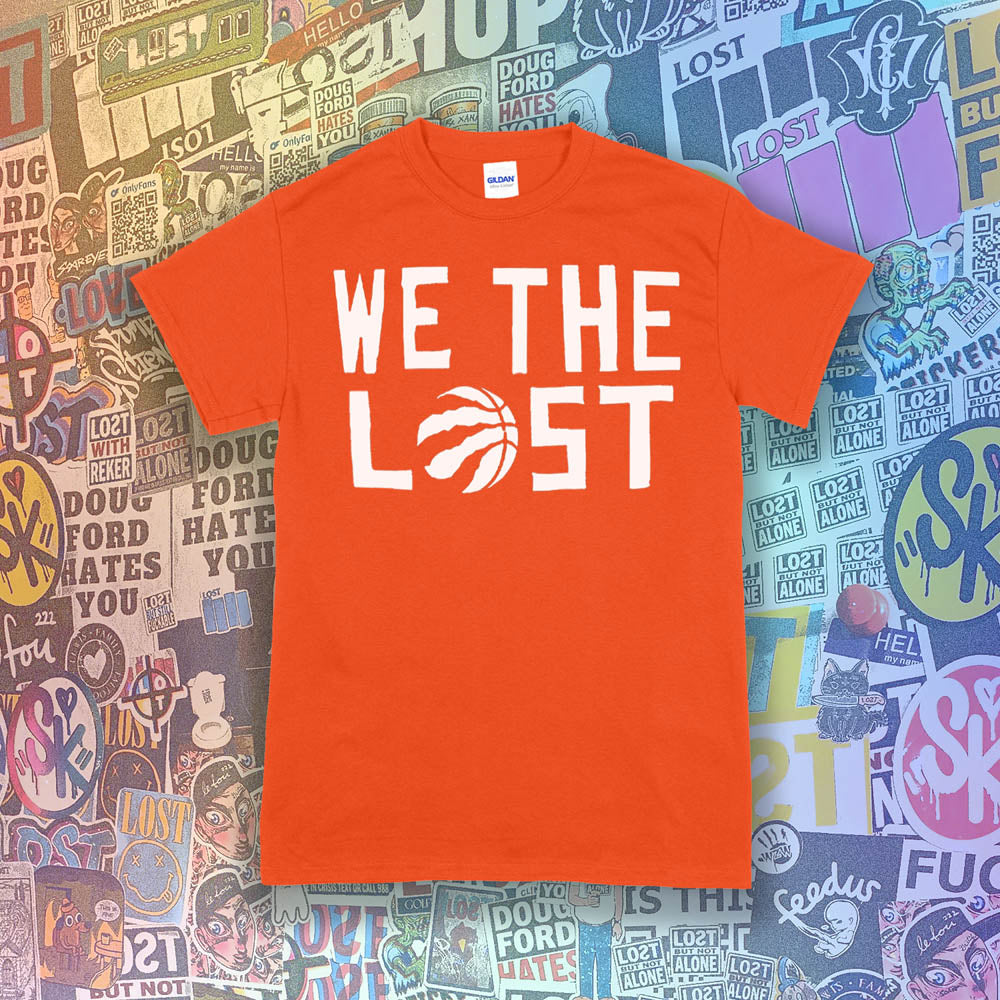 The We The Lost t-shirt. Bold white lettering and raptor claw design screen printed onto a bright orange colored shirt. A wall of brightly colored graffiti stickers makes up the background.