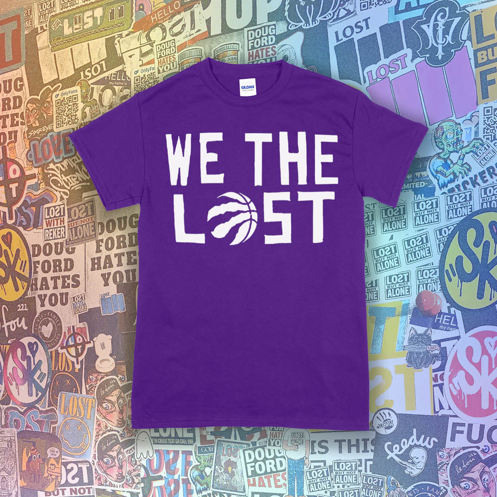The We The Lost t-shirt. Bold white lettering and raptor claw design screen printed onto a purple colored shirt. A wall of brightly colored graffiti stickers makes up the background.