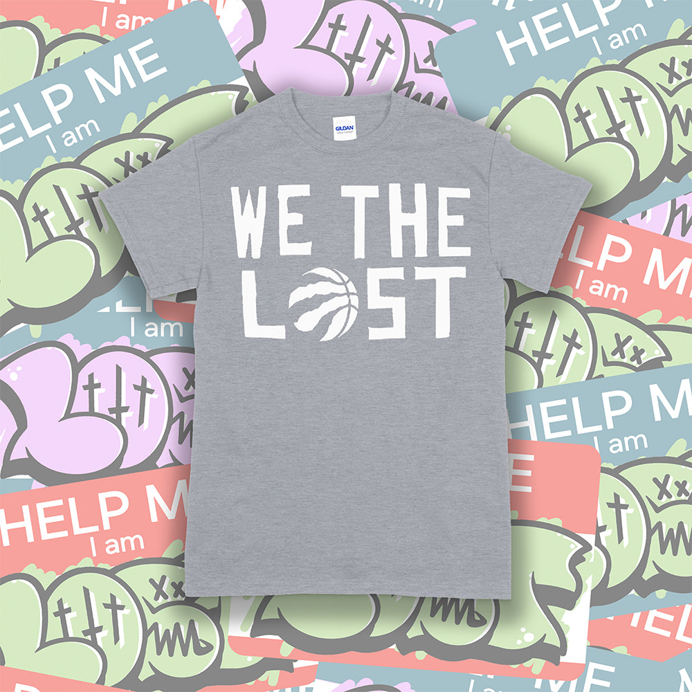 The We The Lost t-shirt. Bold white lettering and raptor claw design screen printed onto a grey colored shirt. A collection of brightly colored graffiti stickers makes up the background.