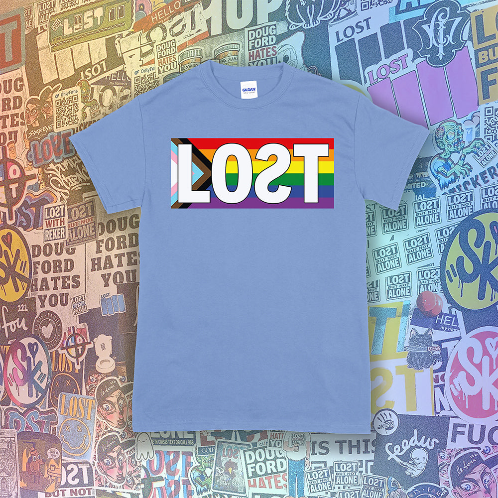 LOST progress flag shirt design by Lost Streetwear. Full color design displayed on a Carolina blue shirt. Graffiti stickers from various artists in the background.